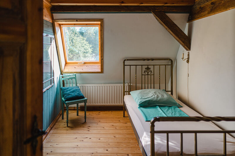 Kleines Zimmer mit Bett und Dachfenster